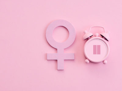 Minimal pink background with female gender symbol and clock illustrating red light therapy and female hormones.