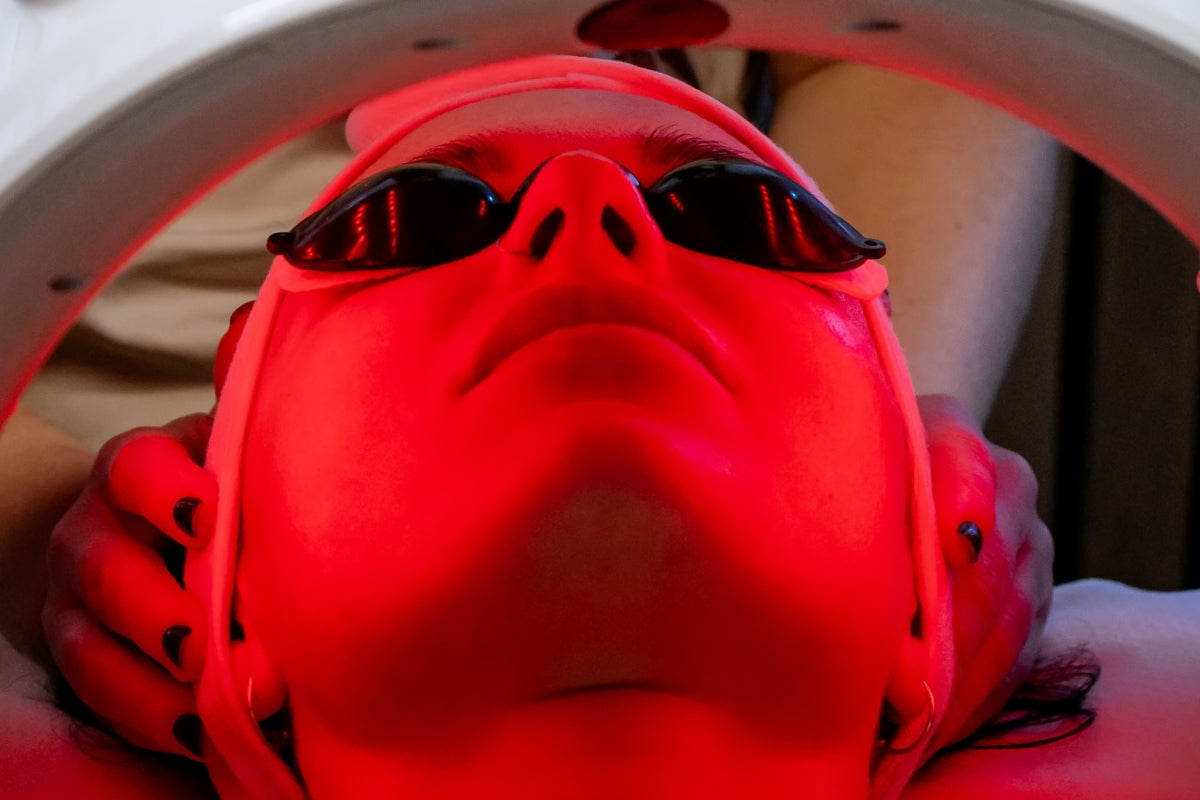 Person receiving red light therapy treatment while wearing protective eyewear.