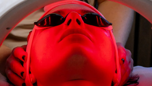 Person receiving red light therapy treatment while wearing protective eyewear.