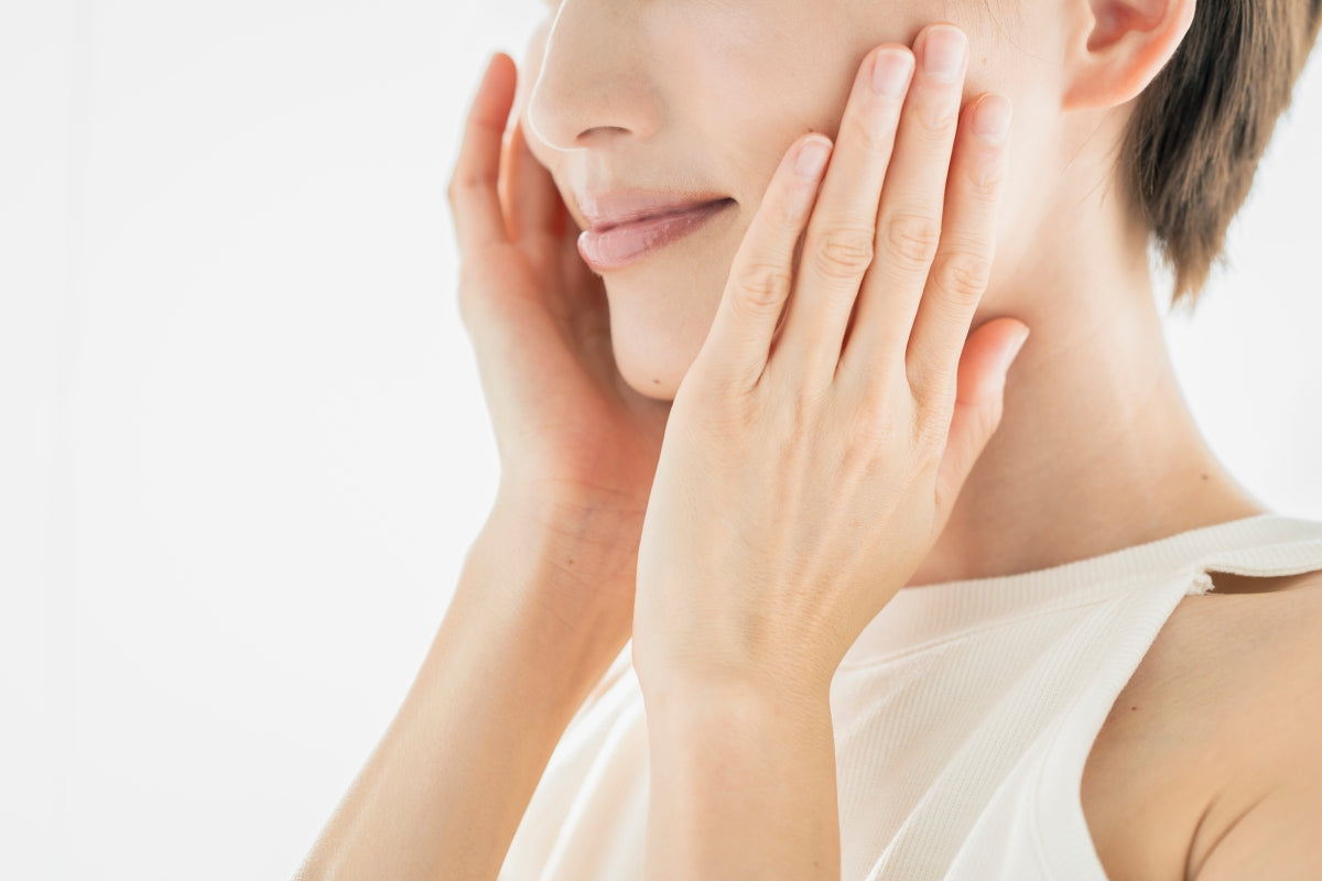Woman touching her cheek to check her skin after comparing qure microneedling vs dr pen options