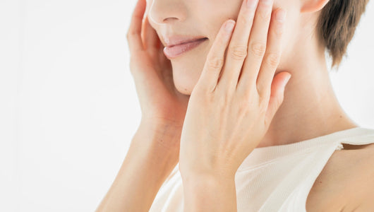 Woman touching her cheek to check her skin after comparing qure microneedling vs dr pen options