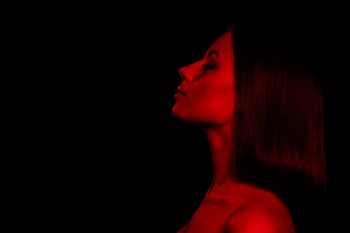 Woman using red light therapy at home, comparing qure vs shark led mask options