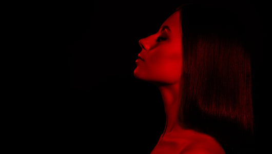 Woman using red light therapy at home, comparing qure vs shark led mask options