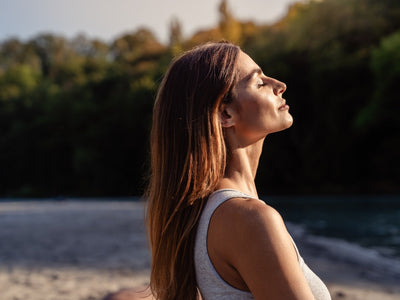 Woman with her face turned to the sun while considering the difference between red light therapy vs sunlight
