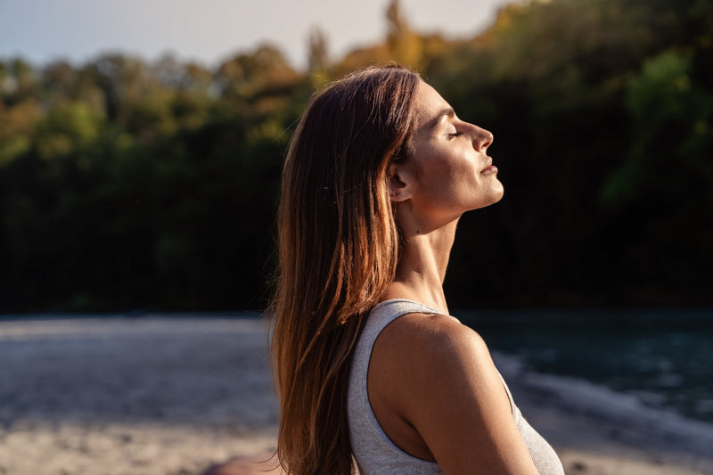 Woman with her face turned to the sun while considering the difference between red light therapy vs sunlight