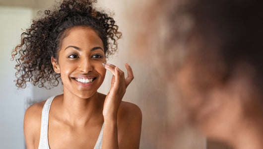 Woman smiling while applying face cream in the mirror
